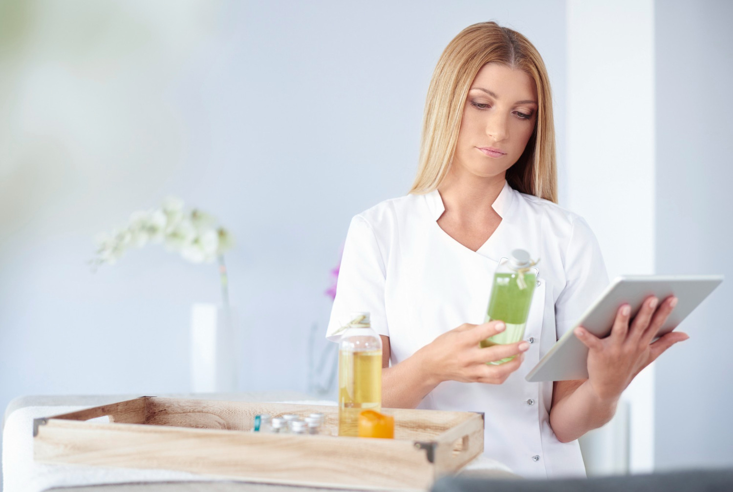 Woman holding a tablet device and weight loss medication, reviewing her treatment plan.