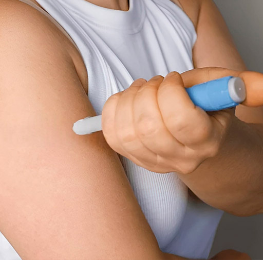 Woman self-injecting medication as part of prescribed treatments at home